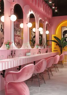 a bathroom with pink chairs and mirrors on the walls, along with lights hanging from the ceiling