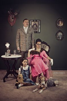 a man and woman sitting on a chair with two children in front of them next to a dog