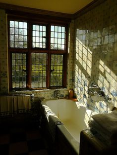 a bath tub sitting next to a window in a room with tiled walls and floor