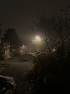 a car parked on the side of a road at night with its headlights turned on