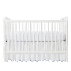 a crib with white bedding and pillows on the bottom row, in front of a white background