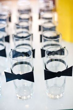 glasses with black bow ties are lined up on a table