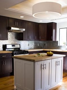 a kitchen with an island in the middle and dark wood cabinets on the other side