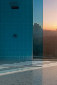 the sun is setting in front of a blue tiled shower