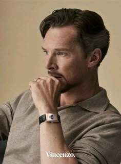 a man with a watch on his wrist looking off to the side while sitting down