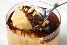 an ice cream sundae with chocolate and nuts on top is being spooned into it