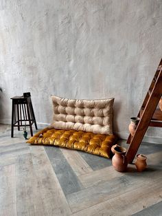 a couch and some vases are on the floor in front of a wall with a ladder