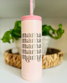 a pink insulated tumbler with the words mama mamma on it sitting next to a potted plant