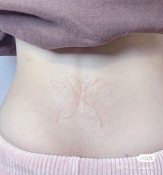 a woman's stomach with a pink butterfly tattoo on her lower back and side