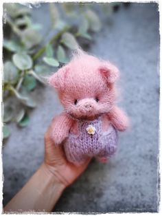 a hand holding a small pink teddy bear