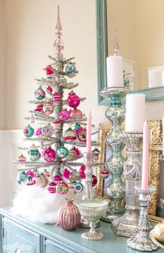 a decorated christmas tree sitting on top of a blue table next to candles and other decorations