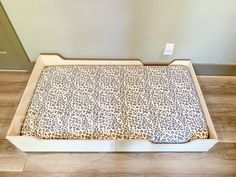 the dog bed is made out of wood and has a leopard print cover on it