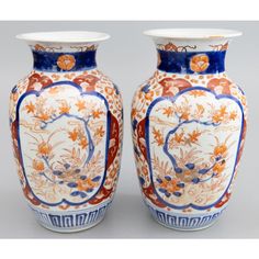 two large vases sitting next to each other on a white surface with orange and blue designs