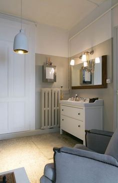 a bathroom with a chair, sink and mirror in it's corner area next to a radiator