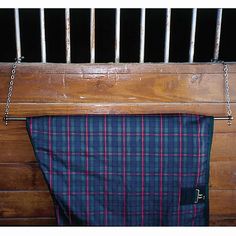 a blue and red plaid blanket hanging on a wooden wall next to a metal railing