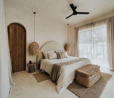 a bedroom with a bed, wicker basket and ceiling fan in the middle of it