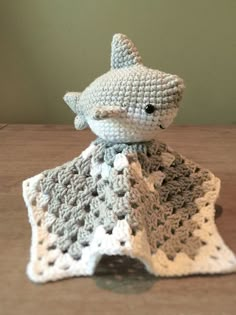 a crocheted stuffed animal sitting on top of a table next to a blanket