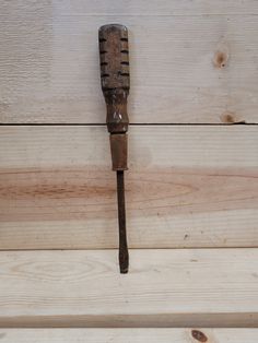 an old wooden comb is hanging on the wall next to a wood planked surface