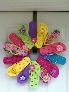 a wreath made out of flip flops and flowers on the front door for someone's house