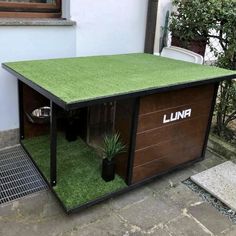 an outdoor dog house with artificial grass on the roof