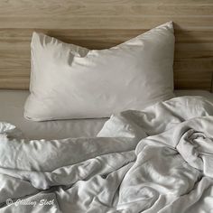 an unmade bed with white sheets and pillows