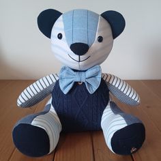 a stuffed animal that is sitting on a wooden table and wearing a blue bow tie