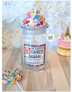 a jar filled with lots of candy and sprinkles on top of a wooden table