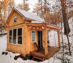 a small wooden cabin in the snow with lights on it's roof and porch