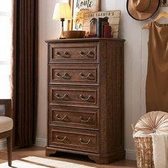 a brown chest of drawers sitting in a room next to a chair and window with a hat on top of it