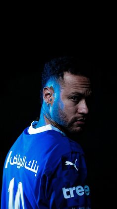 a man with blue paint on his face and chest is looking at the camera while standing in front of a black background