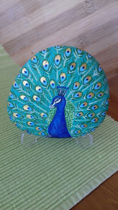 a blue and green peacock sitting on top of a wooden floor next to a rug