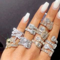 a woman's hand with five different rings on it and one is wearing white nails