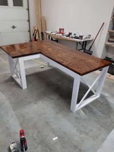 a workbench in a garage with tools on the floor and one bench made out of wood