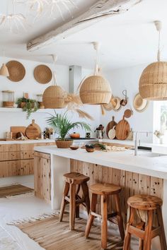 a kitchen filled with lots of wooden stools and hanging baskets above the counter top