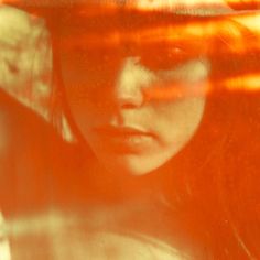 a woman wearing a hat and looking at the camera with an orange tint on her face