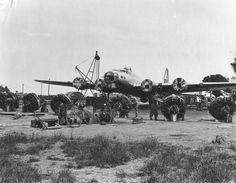 an old black and white photo of some people standing around a plane in the dirt