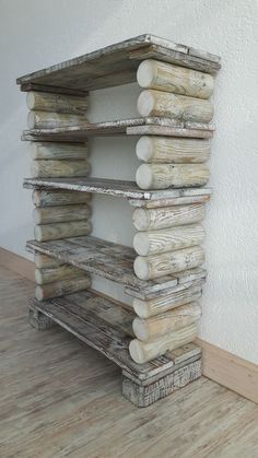 a shelf made out of wooden logs on top of a hard wood floor next to a white wall