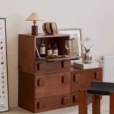 a wooden cabinet sitting next to a table with bottles and glasses on top of it