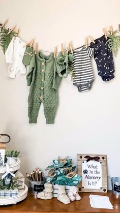 baby clothes are hung on the clothes line above a desk with other items and decorations