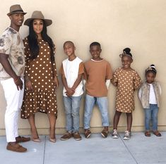 a family poses for a photo in front of a wall with polka dot shirts and hats