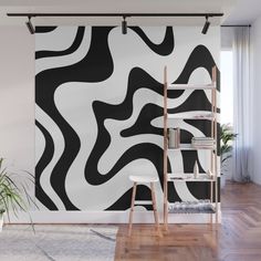 an abstract black and white wall mural in a living room with wooden floors, bookshelves