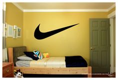 a bed room with a neatly made bed and a black nike logo on the wall