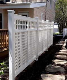 a white privacy fence on the side of a house in front of a brick walkway