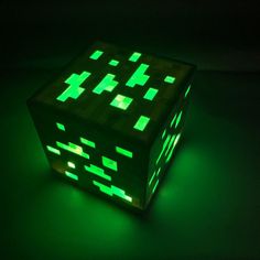 a lit up cube sitting on top of a green floor in the middle of a dark room