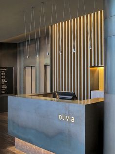 the front desk of an office building with lights hanging from it's ceiling and wood flooring