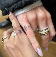 two people with matching rings on their fingers holding each other's hands and one has a flower tattoo on the middle finger