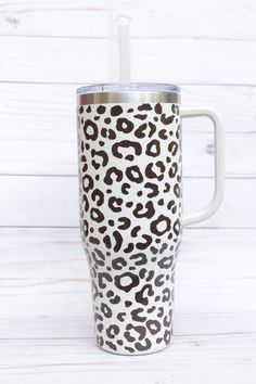 the leopard print tumbler cup has a straw in it and is sitting on a white surface