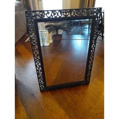 a mirror sitting on top of a wooden floor next to a table with a potted plant