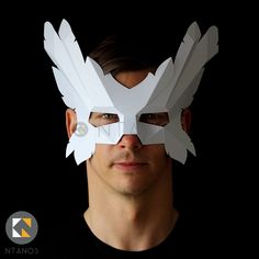 a man wearing a paper mask with white feathers on it's face and eyes