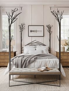 a bed with white sheets and pillows in a bedroom next to two trees on the wall